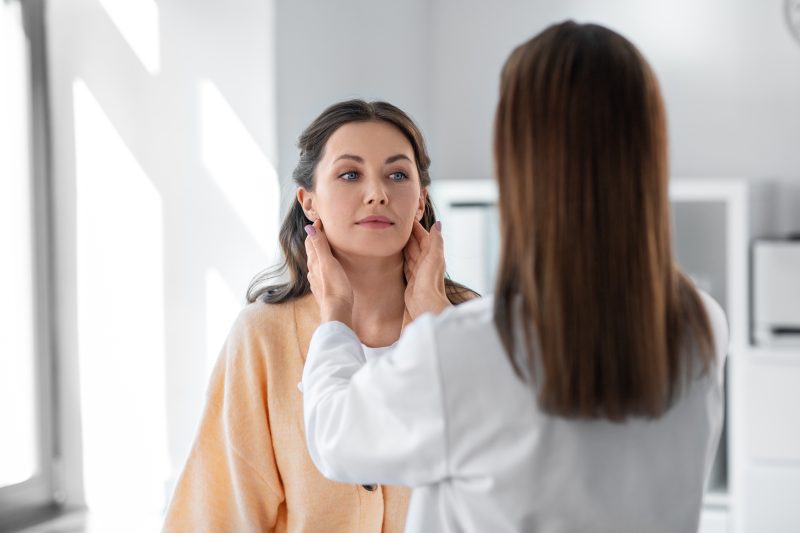 Doctor checking lymph nodes of woman at hospital